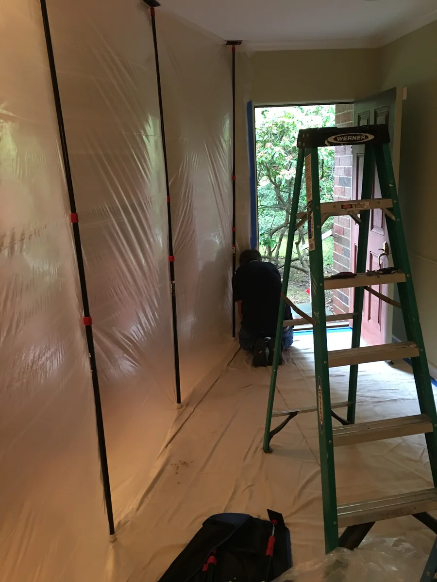 Plastic containment barrier being installed to seal off attic during decontamination