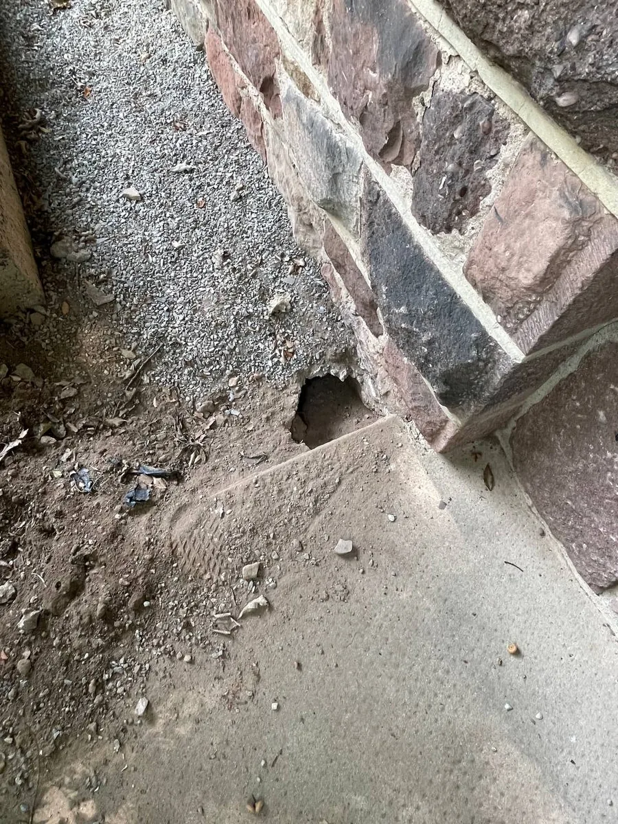 Groundhog burrow dug under the edge of a home's foundation