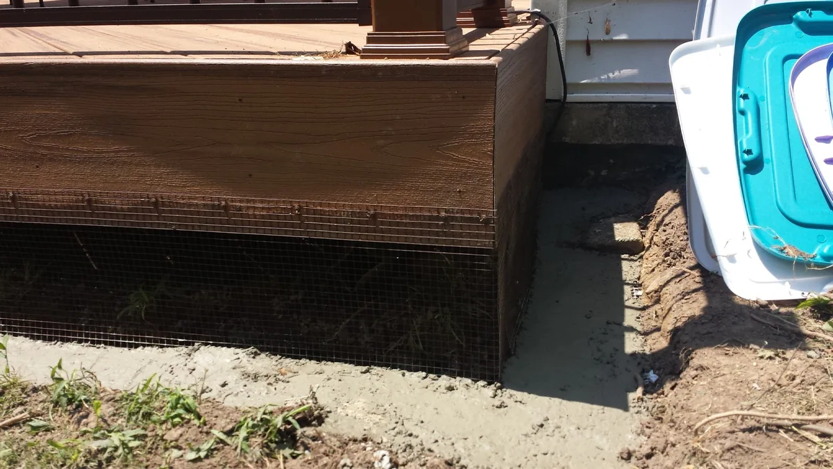 Metal barrier and cement installed along the base of a deck to keep rats out