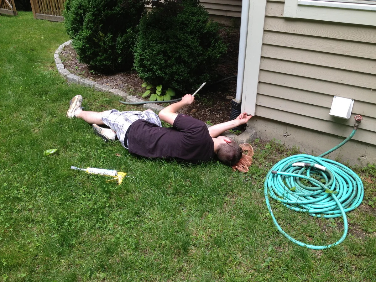 Technician packing copper mesh into foundation gaps to seal out mice