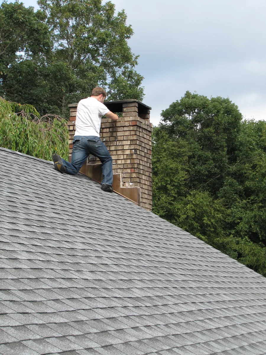 Technician on a roof inspecting a chimney