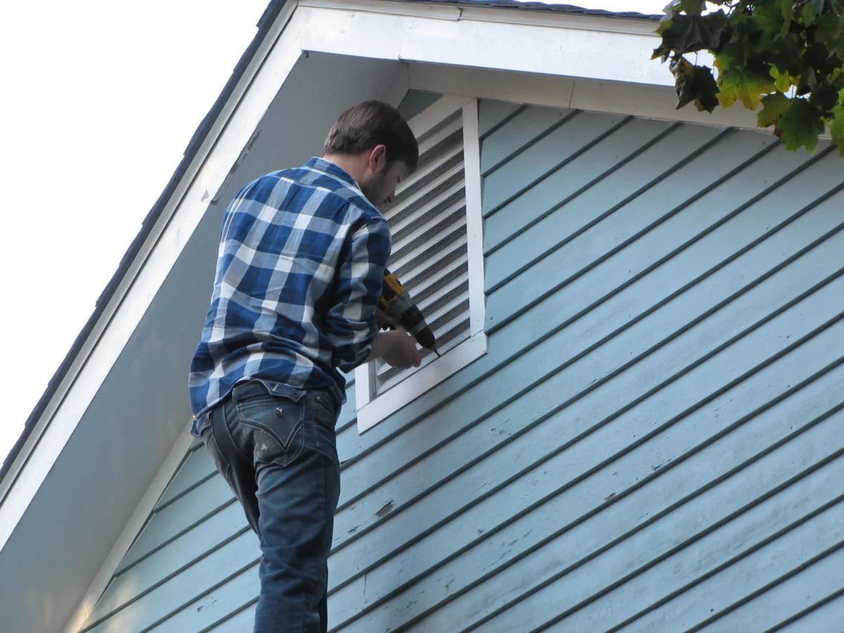Technician installing a custom painted vent cover for bat exclusion
